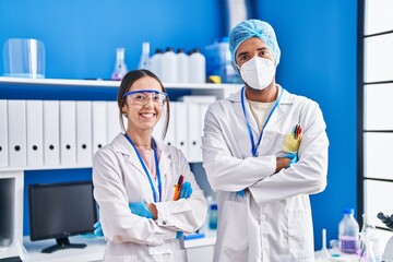 Man and woman scientists smiling confident standing with arms crossed gesture at laboratory