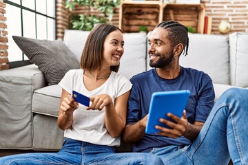 Man and woman couple using credit card and touchpad at home