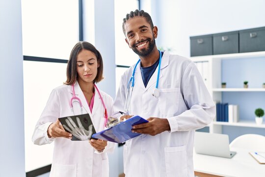Man and woman wearing doctor uniform smiling confident looking xray at clinic