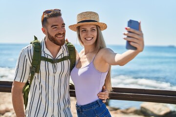 Man and woman tourist couple smiling confident make selfie by smartphone at seaside