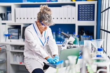 Middle age woman scientist using laptop at laboratory