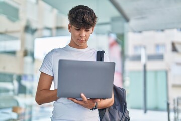 Young hispanic teenager student using laptop with relaxed expression at university