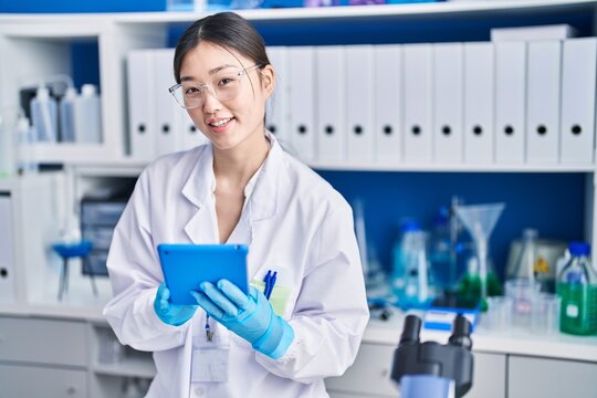 Chinese woman scientist using touchpad working at laboratory