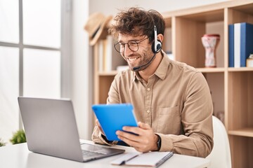 Young man call center agent using touchpad and laptop at office