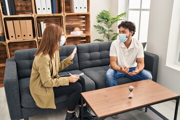 Fototapeta premium Man and woman wearing medical mask having psychology session at psychology center