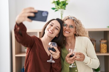 Two women mother and daughter drinking wine make selfie by smartphone at home