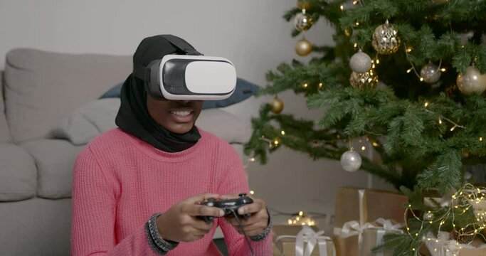 Black muslim girl playing a video game with a controller
