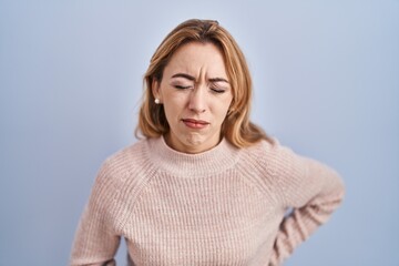 Hispanic woman standing over blue background with hand on stomach because indigestion, painful illness feeling unwell. ache concept.