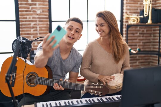 Man and woman musicians having classic guitar lesson make selfie by the smartphone at music studio