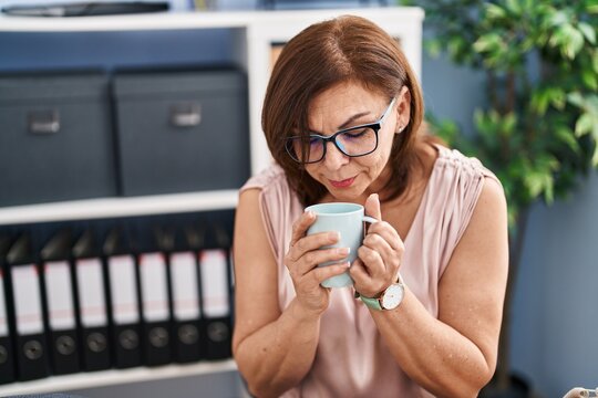 Middle age woman business worker drinking coffee at office