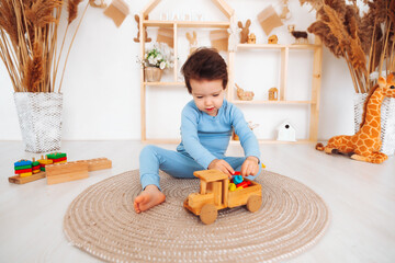 An Asian boy is playing with a small wooden car. A little boy is playing with cubes, smiling. the child is sitting on the floor and playing with a typewriter