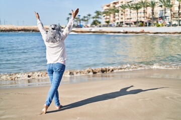 Middle age woman stretching arms at seaside