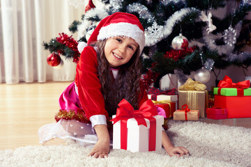 Winter holidays and people concept. Happy young womanl with gifts in boxes standing near a decorated Christmas tree at home