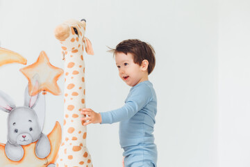 a little boy in a children's playroom with a wigwam and a giraffe playing with wooden toys with...