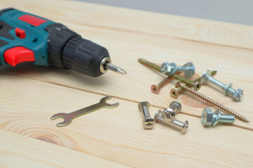 set of tools on wooden table, a electric screwdriver with a set of drill bits and screws with...