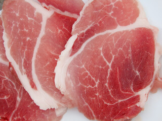 Slide raw meat. Slide top round raw pork meat slices on a white plate