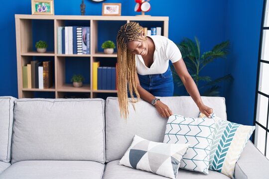 African american woman smiling confident organize sofa at home