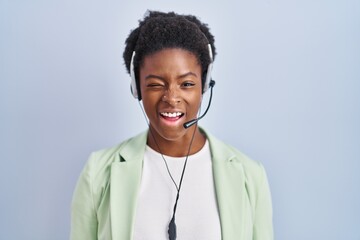 African american woman wearing call center agent headset winking looking at the camera with sexy expression, cheerful and happy face.