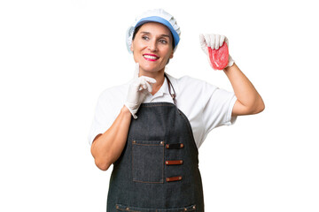 Butcher woman wearing an apron and serving fresh cut meat over isolated background thinking an idea while looking up
