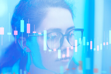 Investments and stock trading. Defocused portrait of a young business woman wearing eyeglasses looking at charts and diagrams, double exposure. The concept of analytics, cryptocurrencies and nft