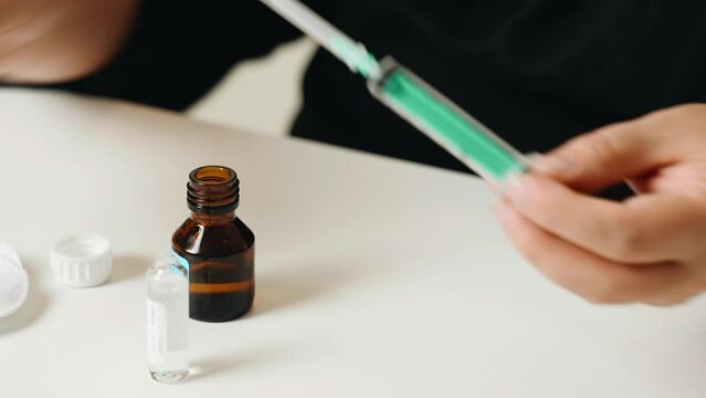 Treatment at home. A woman opens a syringe and collects medicine from an ampoule with medicines. Close-up.
