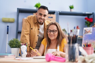 Man and woman artists smiling confident drawing on notebook at art studio