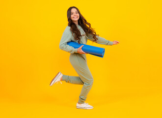 Fototapeta na wymiar Sportswear advertising concept. Teenager child girl in tracksuits jogging suit posing in the studio hold fitness mat. Run and jump.