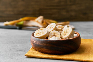 Photo of banana slices in a bowl on a concrete surface
