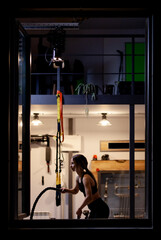 Fit girl practicing with ropes in a fitness studio. View from outsite the window.