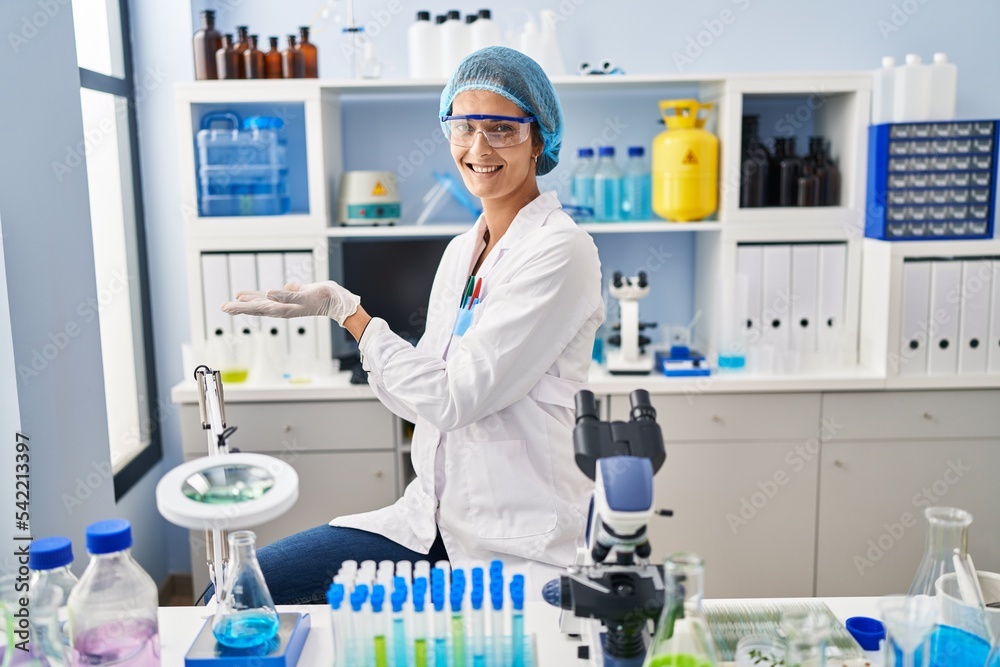 Poster brunette woman working at scientist laboratory pointing aside with hands open palms showing copy spa