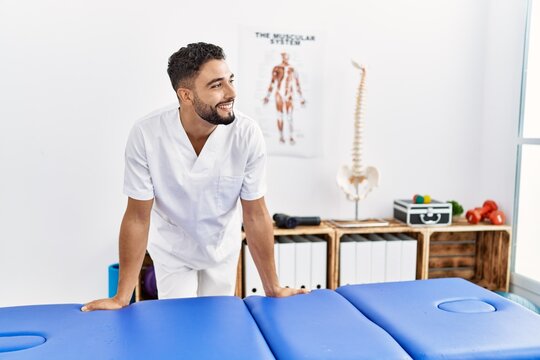 Young arab man wearing physiotherapist uniform standing at clinic