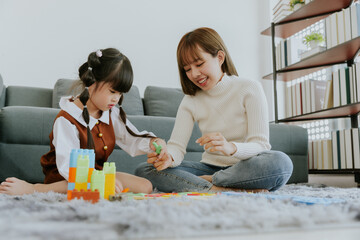 Mom and little 4 years old kid daughter playing education toy together at living room