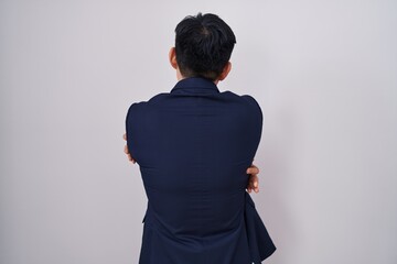 Young asian man wearing business suit and tie hugging oneself happy and positive from backwards. self love and self care