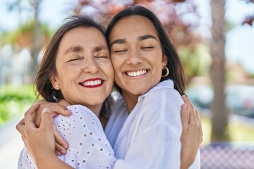 Two women mother and daughter smiling confident hugging each other at park