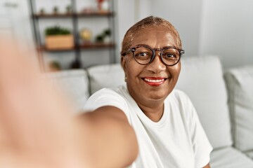 Senior african american woman make selfie by the camera sitting on sofa at home - Powered by Adobe