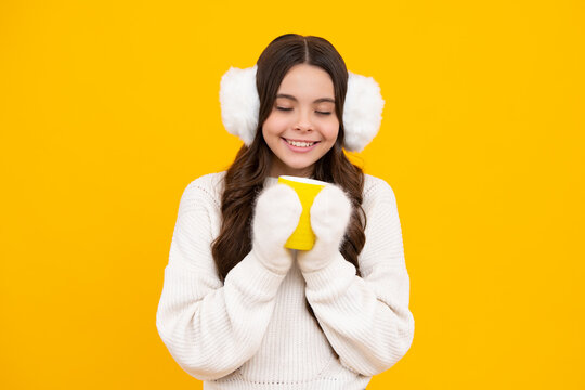 Teen girl in winter warm earmuff ear-flaps and sweater with take away cup of cappuccino coffee or tea. Child with plastic takeaway mug, morning drink cocoa beverage.
