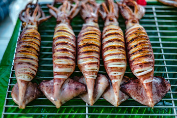 Squid with eggs grilled on a charcoal grill for sale in the local seafood market, Won Beach, Bangsaen, Thailand.