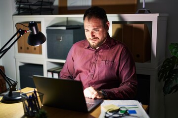 Fototapeta premium Plus size hispanic man with beard working at the office at night depressed and worry for distress, crying angry and afraid. sad expression.