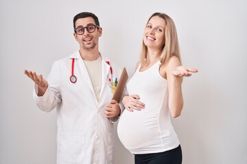 Young woman expecting a baby with doctor celebrating achievement with happy smile and winner...