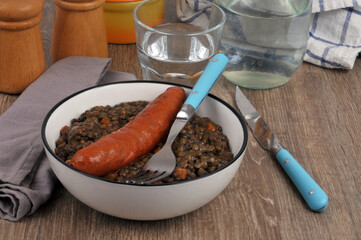Assiette de lentilles et saucisse avec des couverts et une verre d'eau