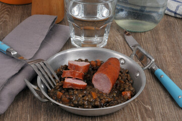 Plat de lentilles et saucisse avec une fourchette et un verre d'eau en gros plan