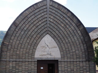 fachada frontal de la iglesia parroquial de el pont de suert construida por un ingeniero de caminos, construcción contemporánea, diez arquivoltas y una escultura de la virfgen envuelta en su cabello, 