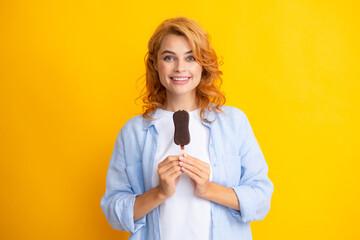 Portrait of beautiful woman eating ice cream on orange yellow background. Girl eating popsicle ice pop. Happy excited expression female portrait.
