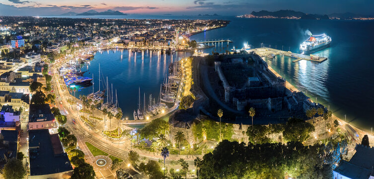 Port of Kos. Kos Island, Greece. Panoramic, early evening aerial view of the harbour lagoon with yachts and the tourist centre with illuminated promenade. A well-known tourist spot.