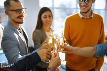 Group of young business people toasting each other and smiling while standing in the office.Partners celebrating their victory. Birthday, new year, christmas concept.
