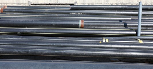black pipes in the deposit of building material on the road cons