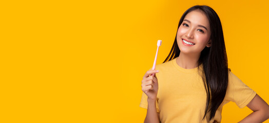 Happy woman brushing beauty tooth using toothbrush Young lady has beauty teeth Beautiful asian girl get strong tooth white teeth and nice tooth alignment Yellow background Copy space Dental Care