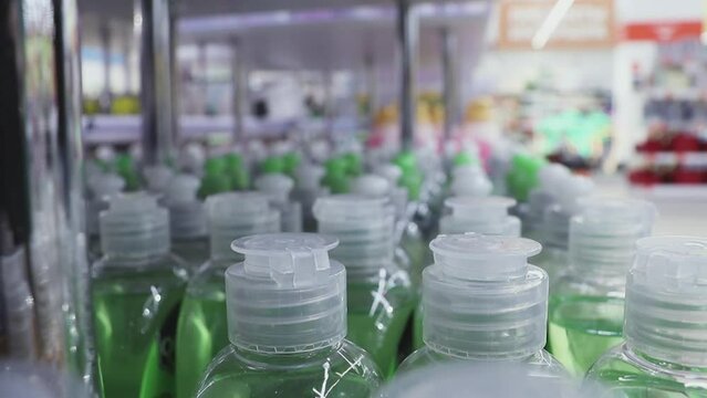 Close-up of many bottles of liquid soap on a store shelf and a man takes one