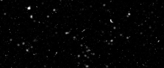 Falling snow isolated on black background. Falling snow at night. Bokeh lights on black background, flying snowflakes in the air. Winter weather. Overlay texture.	