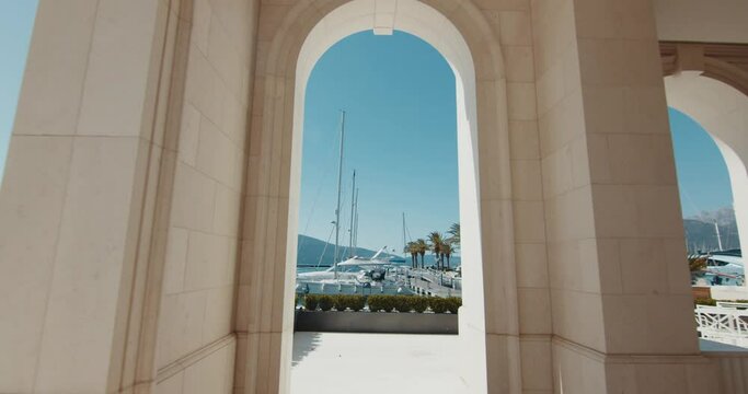 Santa Barbara serial style and camera zooms back from the view of the yachts through the columns of the hotel